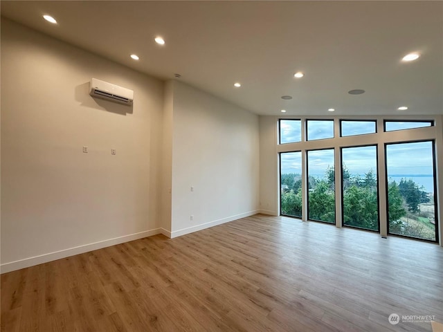 unfurnished room featuring light hardwood / wood-style floors and a wall unit AC