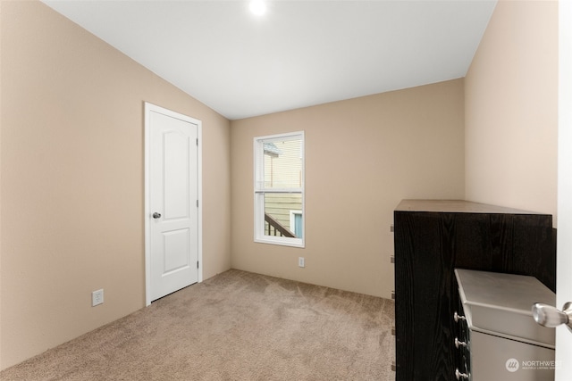 unfurnished bedroom with vaulted ceiling and light carpet