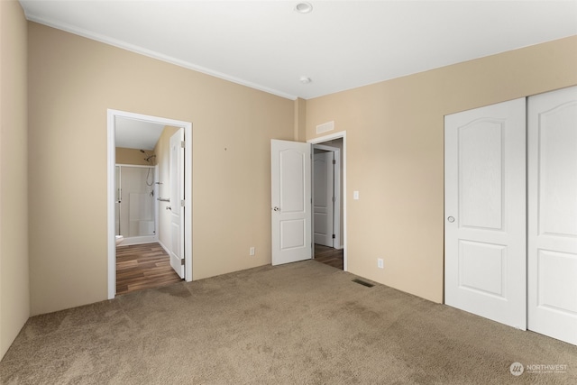 unfurnished bedroom with carpet flooring, ensuite bathroom, and a closet