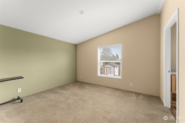 unfurnished room featuring vaulted ceiling and light colored carpet