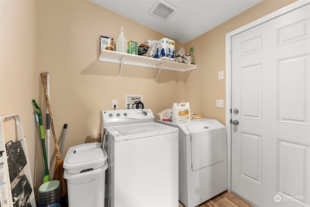 washroom with washing machine and clothes dryer and light hardwood / wood-style flooring