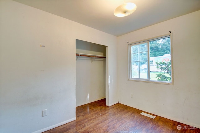 unfurnished bedroom featuring a closet and dark wood-type flooring