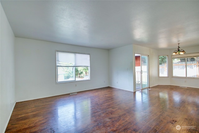 unfurnished room featuring a notable chandelier and dark hardwood / wood-style floors