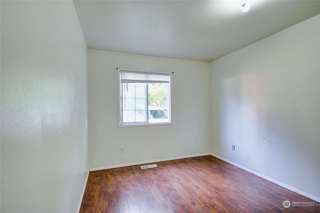 unfurnished room with dark wood-type flooring