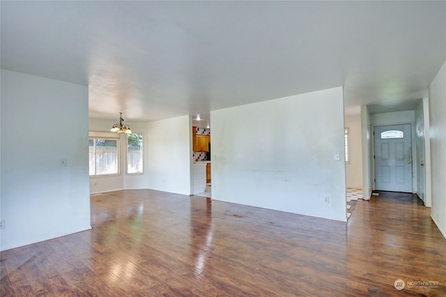 empty room featuring an inviting chandelier and dark hardwood / wood-style flooring