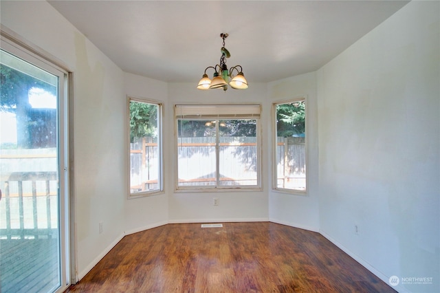 unfurnished dining area with plenty of natural light, a chandelier, and dark hardwood / wood-style floors