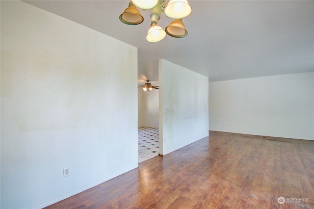 spare room featuring ceiling fan with notable chandelier and dark hardwood / wood-style floors