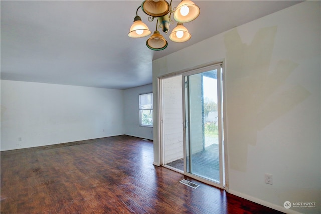 unfurnished room featuring a notable chandelier and dark wood-type flooring