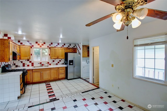 kitchen with decorative backsplash, white range, washer / dryer, stainless steel refrigerator with ice dispenser, and sink