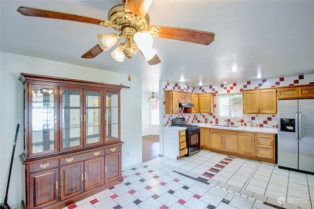 kitchen with ceiling fan, stainless steel fridge, sink, tasteful backsplash, and black range with gas cooktop