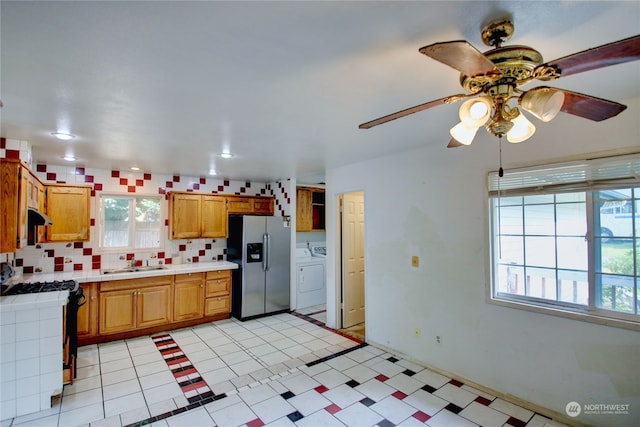 kitchen with backsplash, stainless steel refrigerator with ice dispenser, plenty of natural light, and white gas range