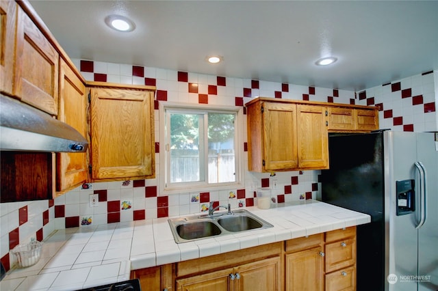 kitchen with decorative backsplash, sink, stainless steel fridge with ice dispenser, and tile countertops