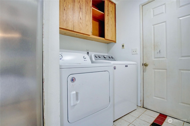 laundry area featuring light tile patterned floors, washer and dryer, and cabinets