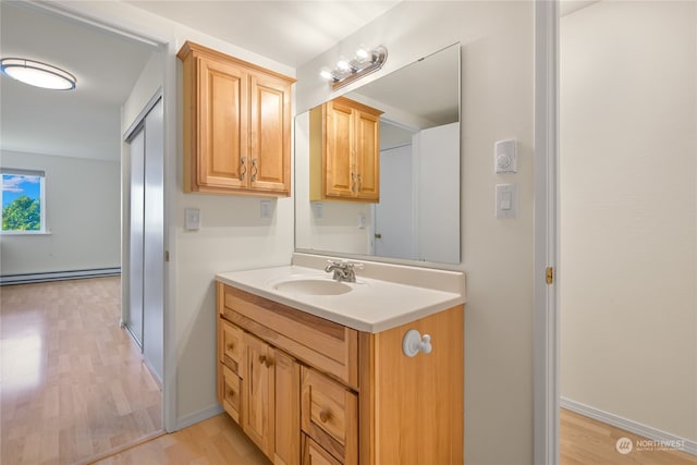 bathroom with hardwood / wood-style floors, vanity, and a baseboard radiator