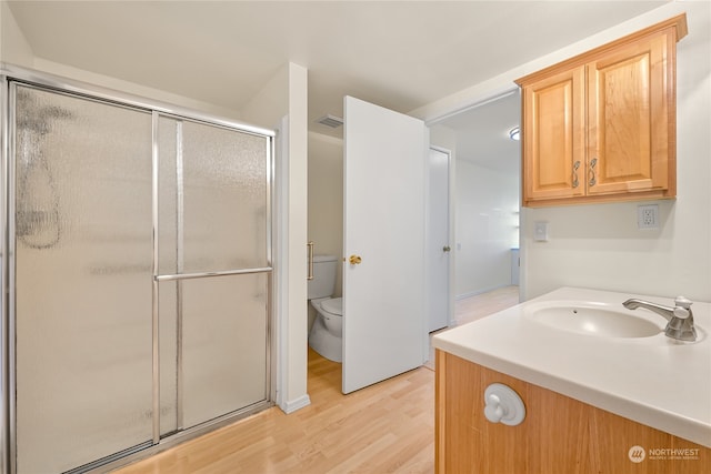 bathroom featuring hardwood / wood-style floors, vanity, toilet, and a shower with door