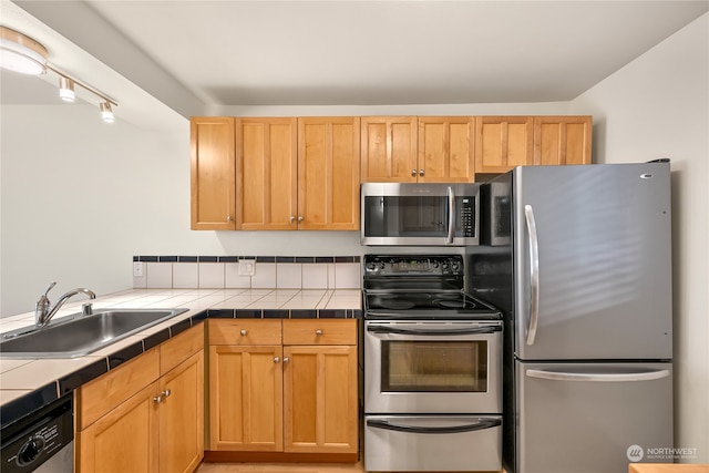 kitchen featuring tile countertops, sink, and appliances with stainless steel finishes