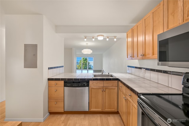 kitchen featuring light wood-type flooring, stainless steel appliances, sink, electric panel, and tile counters