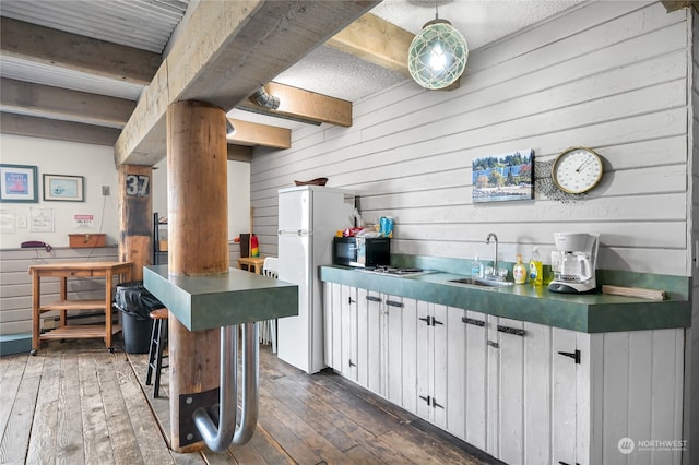 kitchen featuring dark wood-type flooring, white refrigerator, sink, beam ceiling, and white cabinetry