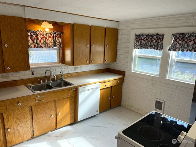 kitchen featuring brick wall, white dishwasher, stove, and sink