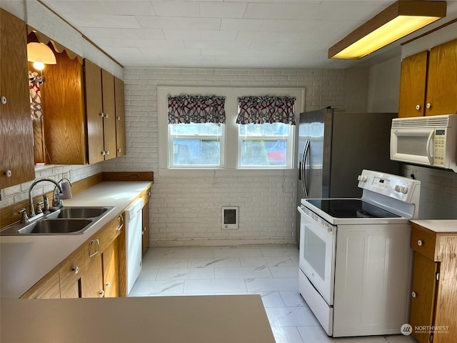 kitchen with a sink, brick wall, white appliances, marble finish floor, and brown cabinetry