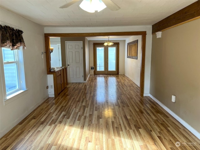 foyer entrance with ceiling fan with notable chandelier, plenty of natural light, and wood finished floors