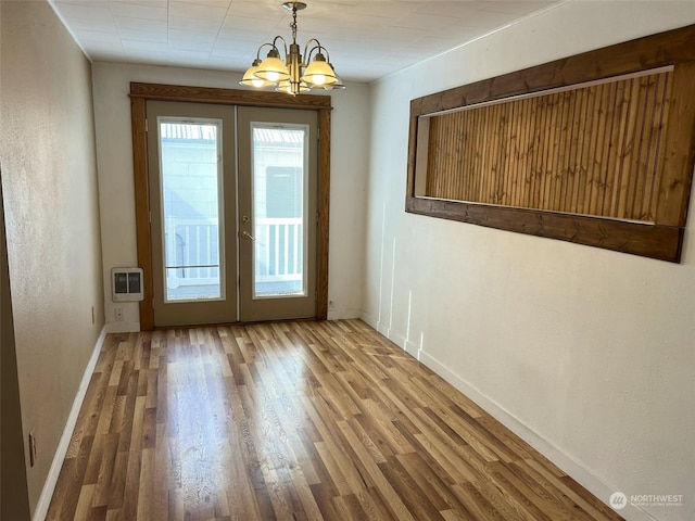 doorway to outside featuring wood finished floors, heating unit, an inviting chandelier, french doors, and baseboards