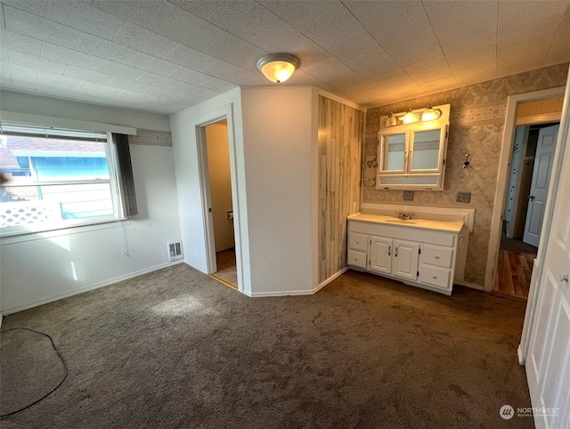 unfurnished bedroom with baseboards, dark colored carpet, visible vents, and a sink
