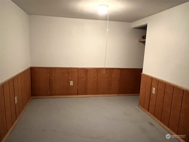 empty room featuring a textured ceiling and wood walls