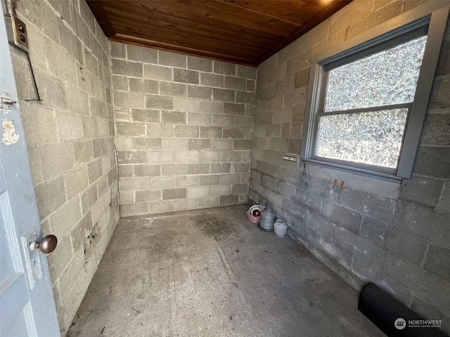 interior space featuring concrete block wall and wooden ceiling