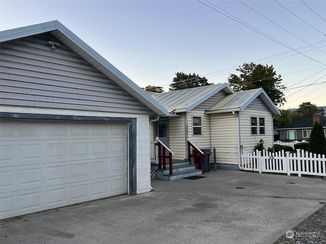single story home with metal roof, fence, driveway, and a garage