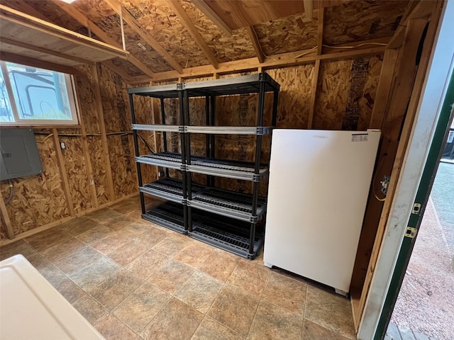 basement featuring electric panel and white fridge