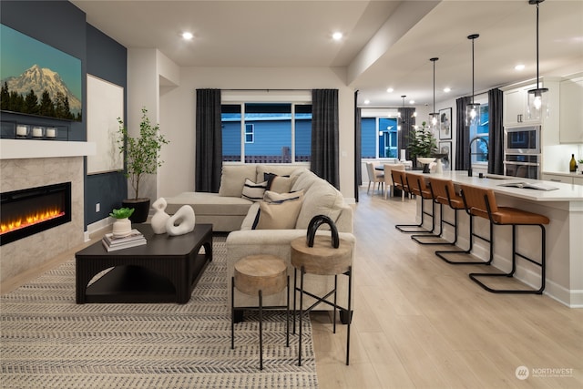 living room featuring light hardwood / wood-style flooring, sink, and a tile fireplace