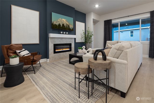 living room with light wood-type flooring and a tiled fireplace