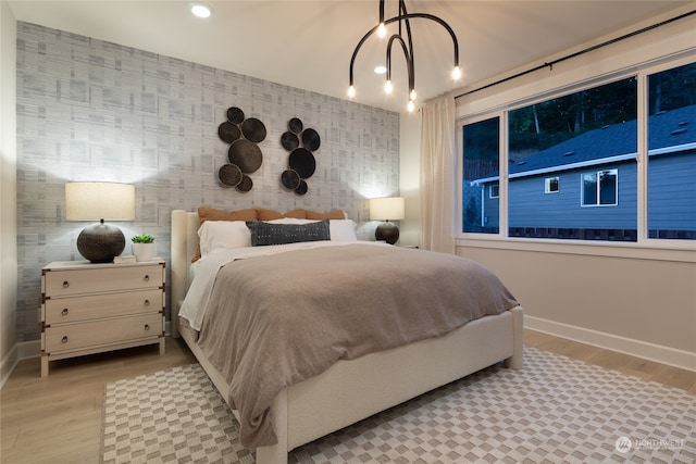 bedroom with a chandelier and light wood-type flooring