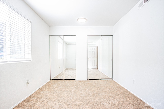 unfurnished bedroom with light carpet and multiple closets