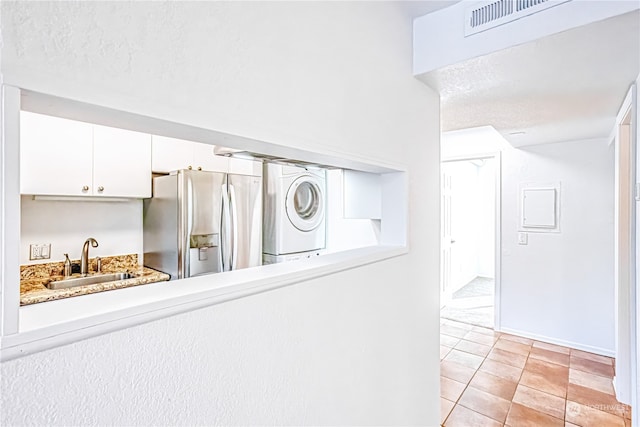 room details with stainless steel fridge, sink, a textured ceiling, washer / dryer, and tile patterned floors