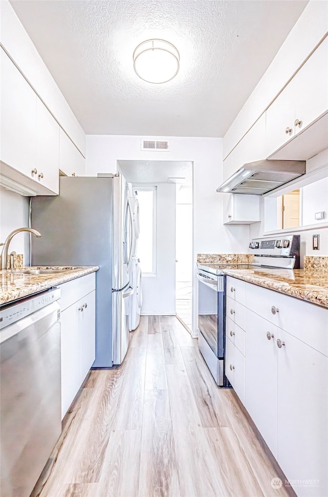 kitchen featuring a textured ceiling, stainless steel appliances, light hardwood / wood-style floors, and white cabinetry