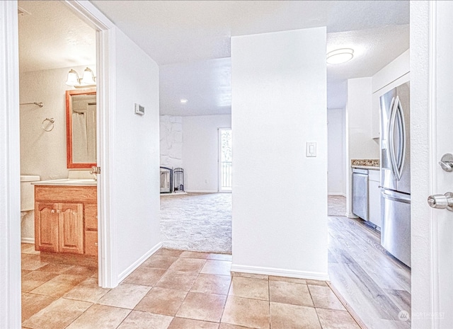 corridor featuring light hardwood / wood-style floors, a textured ceiling, and sink