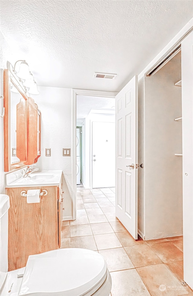 bathroom with tile patterned flooring, a textured ceiling, vanity, and toilet