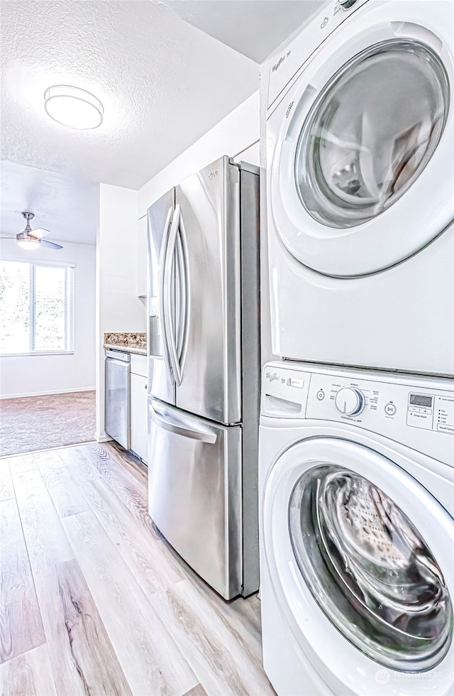 washroom featuring a textured ceiling, stacked washer and dryer, ceiling fan, and light hardwood / wood-style flooring