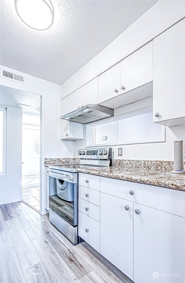 kitchen with light hardwood / wood-style flooring, electric stove, a textured ceiling, and white cabinetry