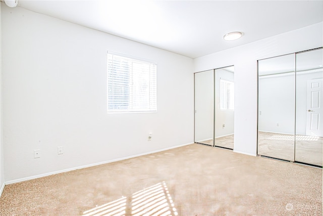 unfurnished bedroom with light carpet and multiple closets