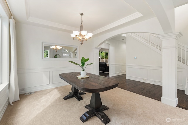 dining area featuring wood-type flooring, ornamental molding, ornate columns, and a chandelier