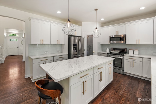 1925 32nd Avenue Ct SW, Puyallup, WA 98373 - kitchen with arched walkways, white cabinets, a kitchen island, dark wood-style flooring, and stainless steel appliances