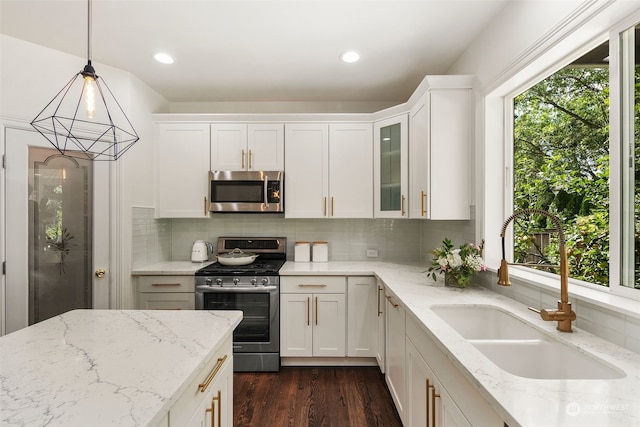 kitchen with white cabinetry, sink, stainless steel appliances, and decorative light fixtures