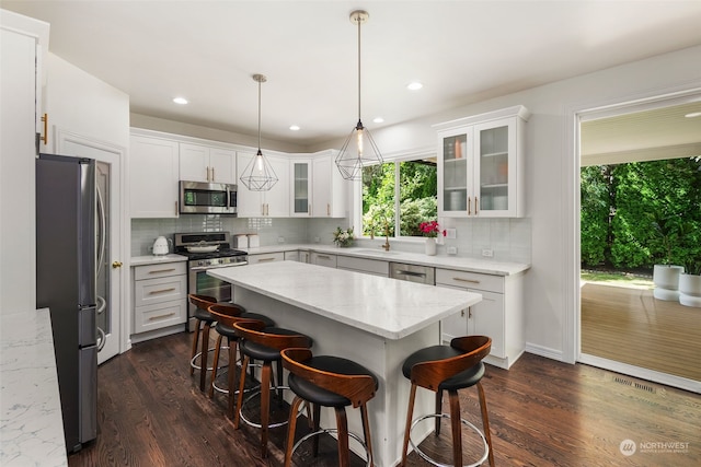 kitchen featuring appliances with stainless steel finishes, plenty of natural light, dark hardwood / wood-style flooring, and white cabinetry