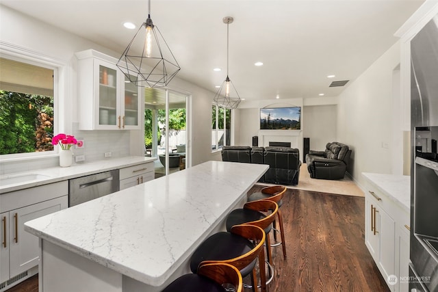 kitchen with white cabinetry, a center island, hanging light fixtures, and a healthy amount of sunlight