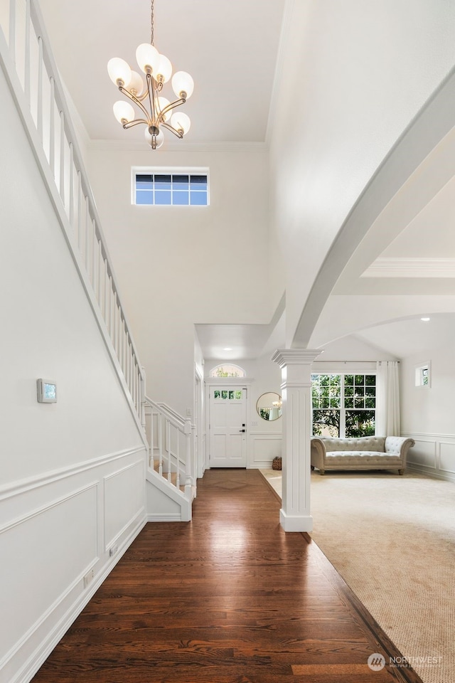 entrance foyer with a chandelier, decorative columns, and dark wood-type flooring