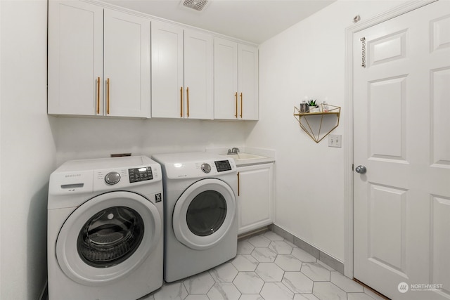 laundry area featuring light tile patterned floors, sink, washing machine and clothes dryer, and cabinets