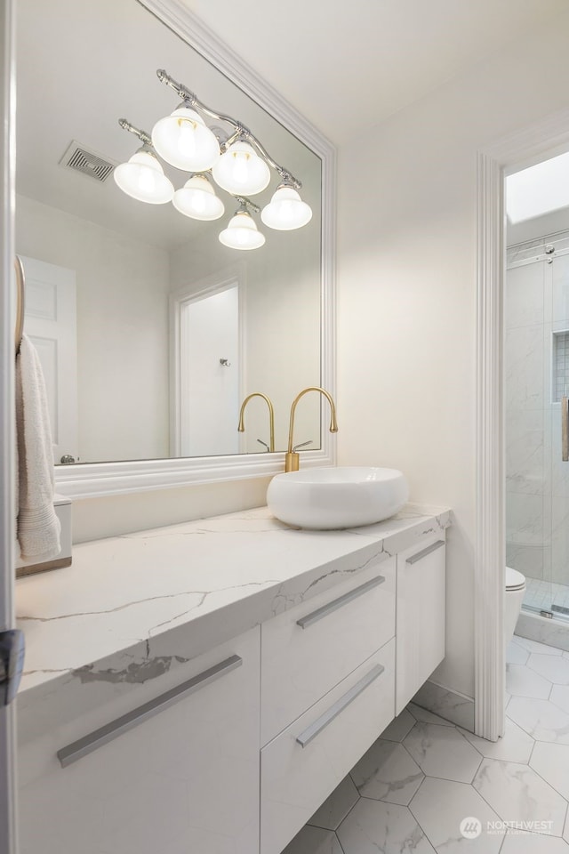 bathroom with vanity, toilet, and a shower with door